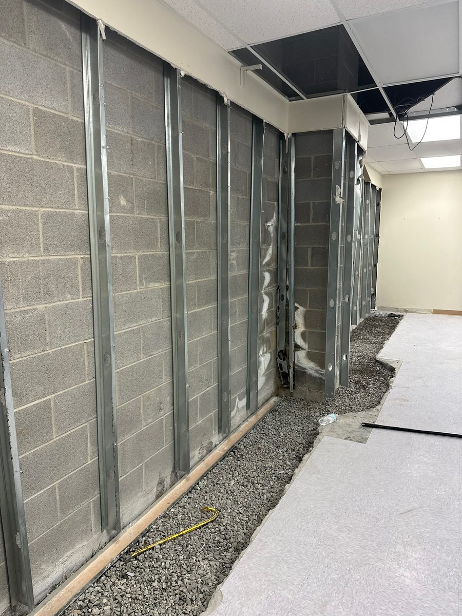 Interior perimeter drainage and gravel bed installed along a basement block wall