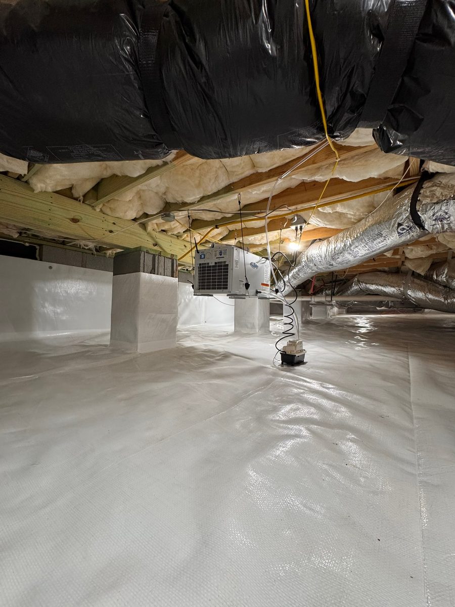 Crawl space encapsulation underway with the moisture barrier being fitted across the ground and piers