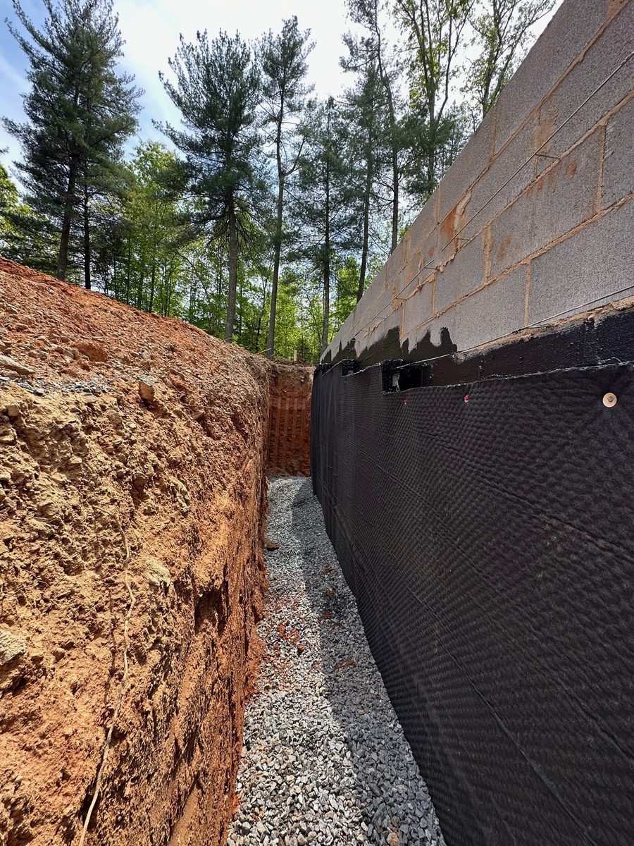 Waterproofing membrane and dimpled drainage board on a new foundation wall before backfill