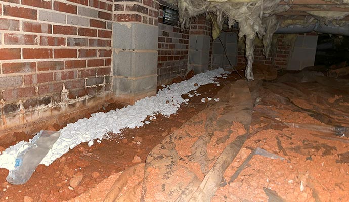 An interior perimeter drain with gravel in a dirt crawl space.