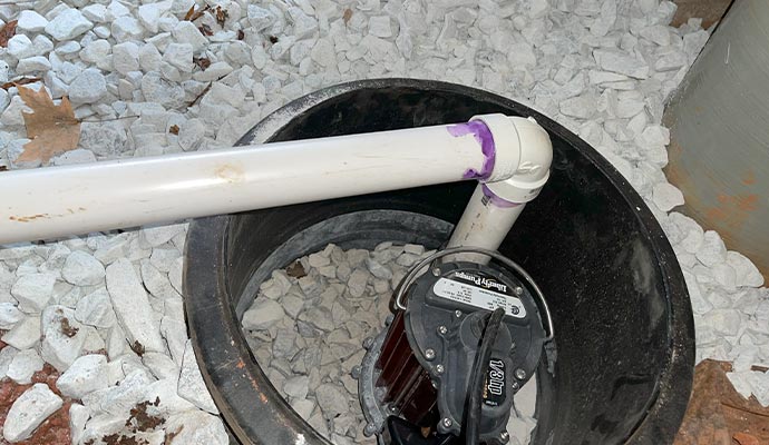 A submersible sump pump inside a basin with a PVC discharge pipe