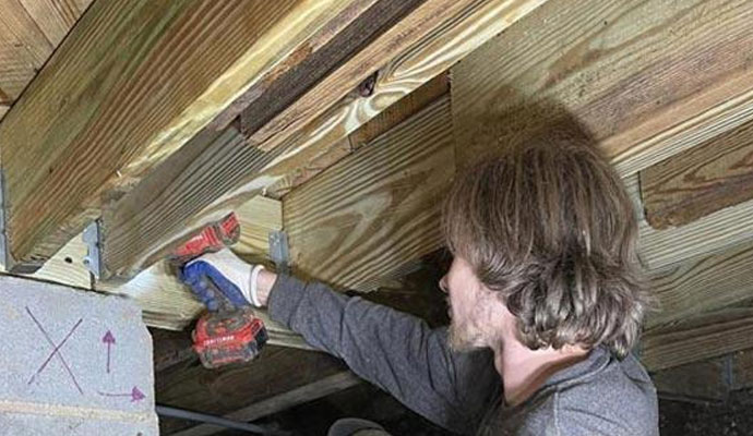 A professional repairing crawl space with equipment