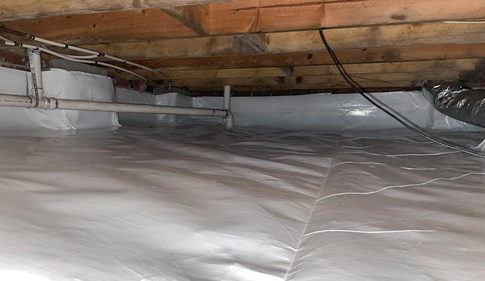 A clean, waterproofed crawl space with a white vapor barrier.
